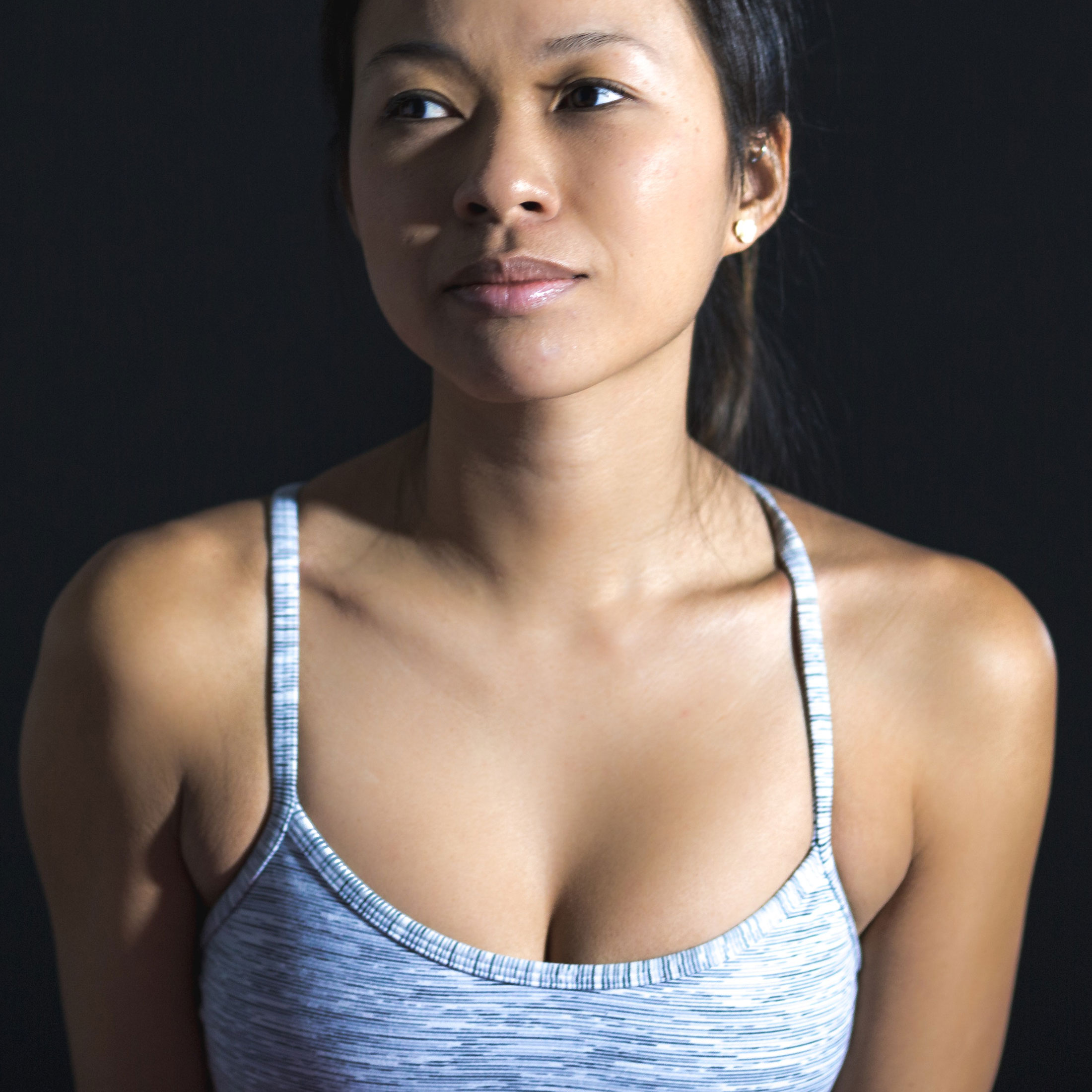 A picture of a woman from the chest up, wearing a grey sports bra.