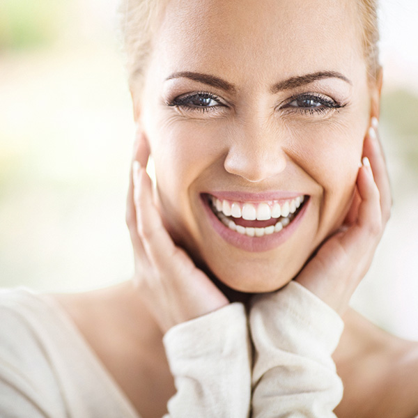 Attractive blonde woman gently touching her chin smiling